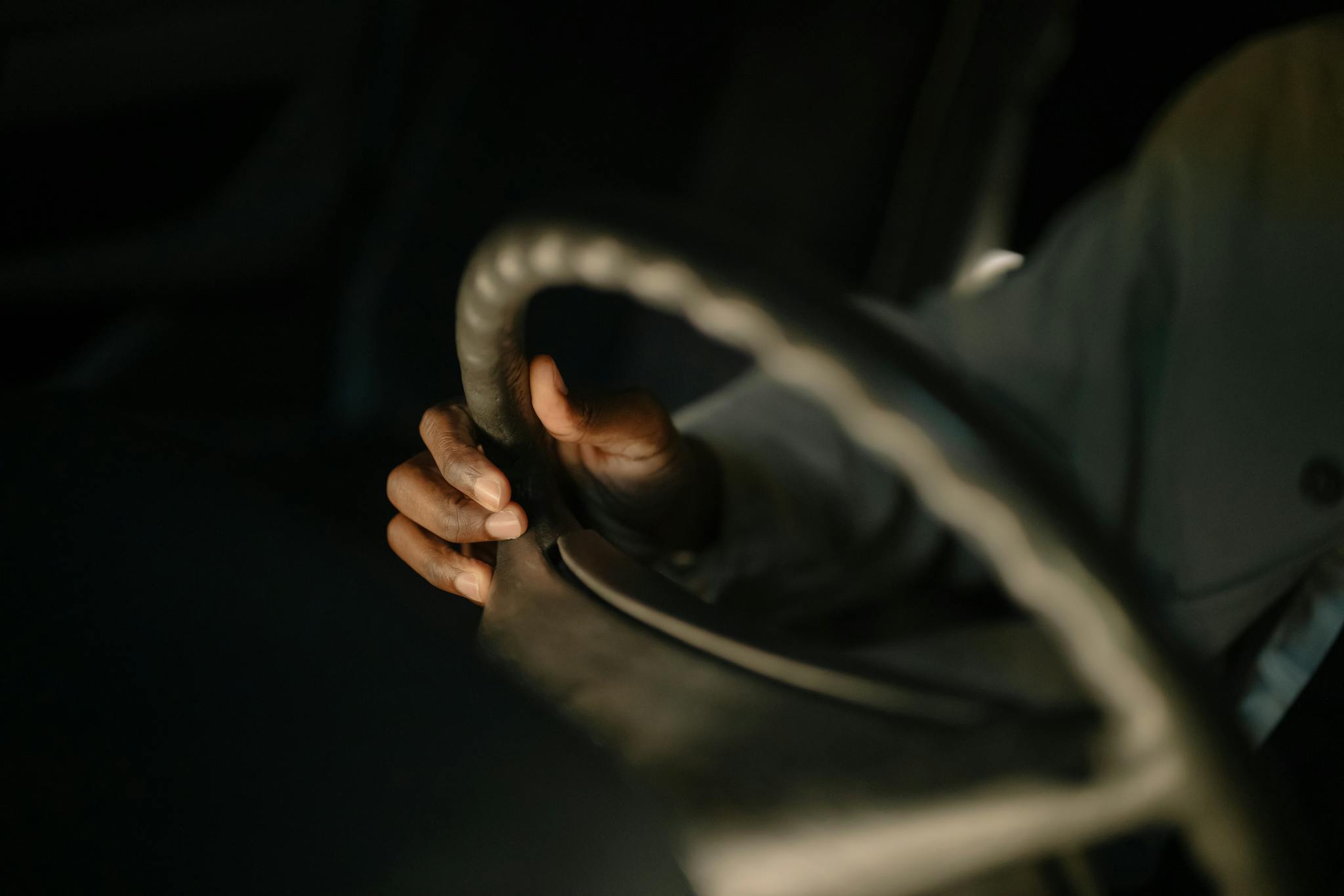 A close-up image of a hand gripping a car steering wheel, highlighting the focus on driving.